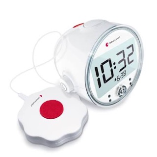 Bellman Väckarklocka Pro med rund display som visar 10:32, kopplad med sladd till den vita sängvibratorn med röd knapp.